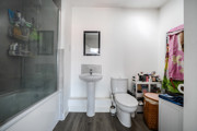 Bathroom with bathtub, shower screen, toilet and pedestal sink.