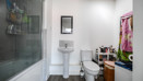 Bathroom with bathtub, shower screen, toilet and pedestal sink.