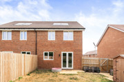 Rear view of the brick house with fenced garden and paved patio area.