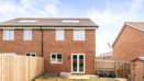 Rear view of the brick house with fenced garden and paved patio area.