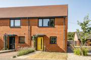Front view of a two-storey brick house with a yellow front door and small front garden.