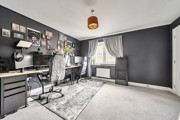 Home office or gaming room with desk, chair, computer screens and dark painted wall.