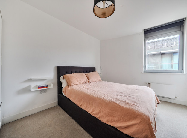 Bedroom with double bed, bedside table and window.