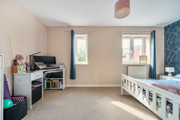 Bedroom with desk, monitors, two windows with curtains and featured wall.