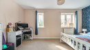 Bedroom with desk, monitors, two windows with curtains and featured wall.