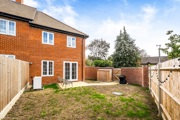 Rear elevation of a red-brick house with enclosed garden and patio.