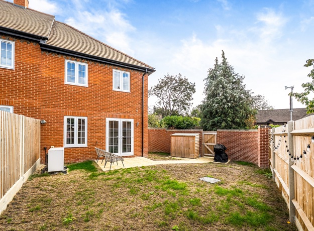 Rear elevation of a red-brick house with enclosed garden and patio.