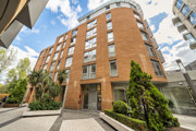 Apartment building with balconies and landscaped area at the entrance.
