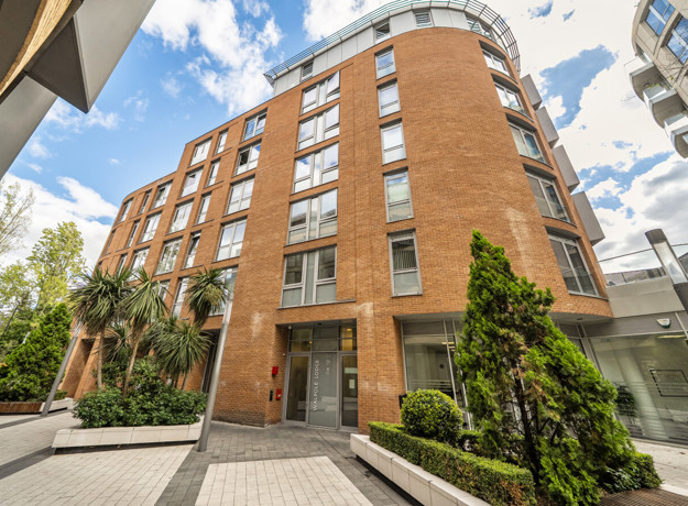 Apartment building with balconies and landscaped area at the entrance.