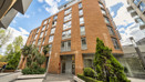 Apartment building with balconies and landscaped area at the entrance.
