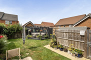 Rear garden with lawn, planted borders, seating area and fenced boundaries.