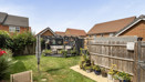 Rear garden with lawn, planted borders, seating area and fenced boundaries.
