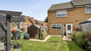 Rear garden with lawn, seating area, shrubs and shed.