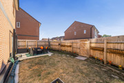 Fenced rear garden with patio area with seating and grass lawn.