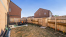 Fenced rear garden with patio area with seating and grass lawn.