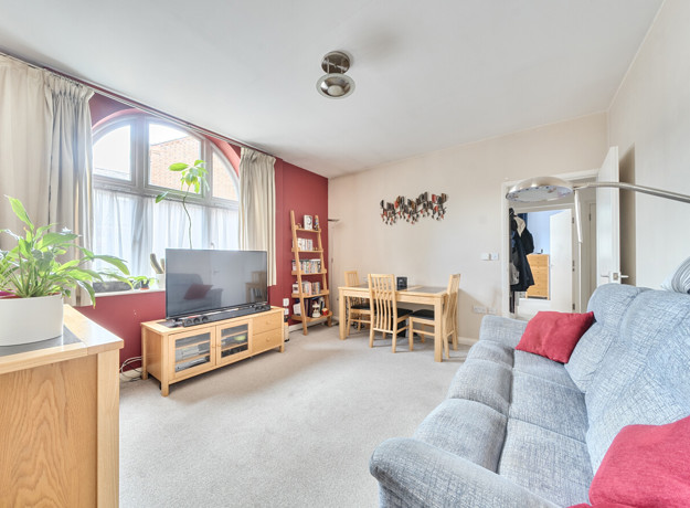 Living room with sofa, television, windows, and a dining table with chairs.