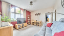 Living room with sofa, television, windows, and a dining table with chairs.