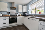 Modern kitchen with white cabinets, appliances and window above sink.
