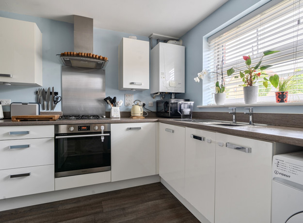 Modern kitchen with white cabinets, appliances and window above sink.