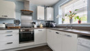 Modern kitchen with white cabinets, appliances and window above sink.