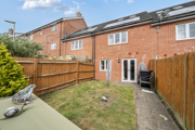 Back garden with grass, fence, patio path, and outdoor storage items.