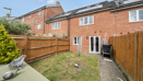 Back garden with grass, fence, patio path, and outdoor storage items.