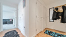Entrance hallway with wood-effect flooring, storage cupboards, coat hooks, and a view towards the living room.