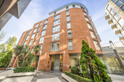Exterior view of apartment building with landscaped entrance and balconies.