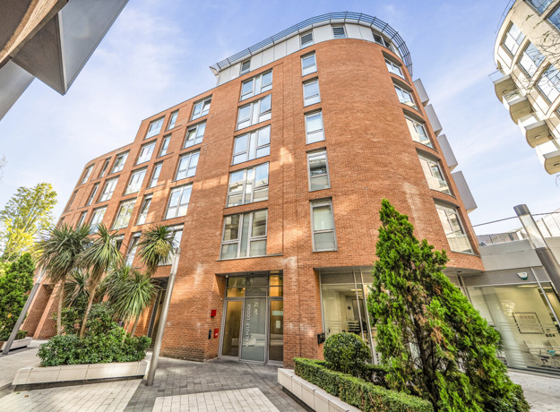 Exterior view of apartment building with landscaped entrance and balconies.