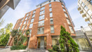 Exterior view of apartment building with landscaped entrance and balconies.