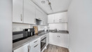 White fitted kitchen with integrated oven, worktops and storage cupboards.
