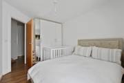 Bedroom with bed, wardrobe, door, and wooden floor.