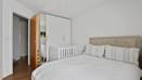 Bedroom with bed, wardrobe, door, and wooden floor.