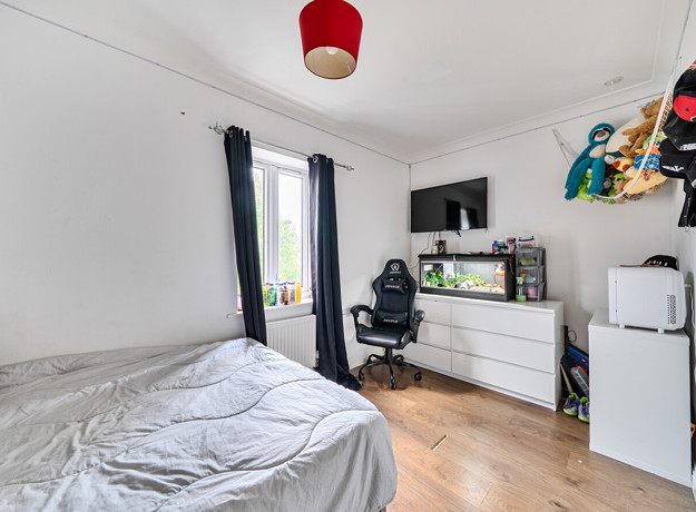 Bedroom with double bed, chest of drawers, television, chair, window and fish tank.