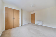 Bedroom with built-in wardrobe, radiator and carpeted floor.