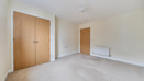Bedroom with built-in wardrobe, radiator and carpeted floor.