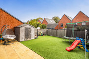 Rear garden with lawn, patio, shed and children's trampoline and slide.