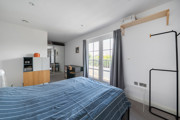 Bedroom with a double bed, wardrobe and balcony doors.