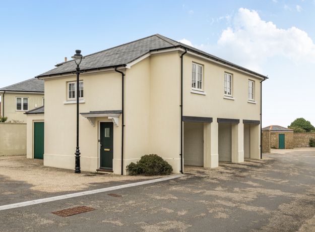 Exterior view of building with garages and paved forecourt in a residential area.