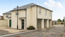 Exterior view of building with garages and paved forecourt in a residential area.