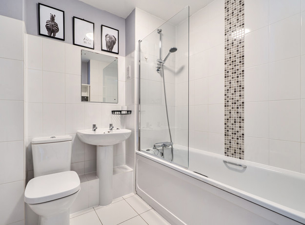 Bathroom with white suite, tiled walls, bathtub, and overhead shower.