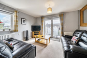 Living room with sofas, TV, coffee table, window and patio doors.
