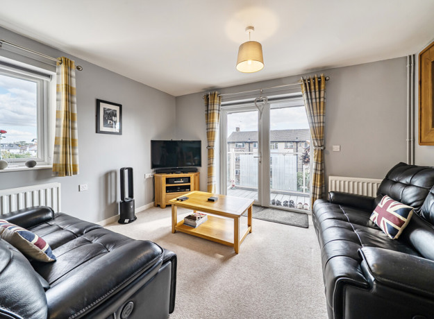 Living room with sofas, TV, coffee table, window and patio doors.