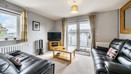 Living room with sofas, TV, coffee table, window and patio doors.