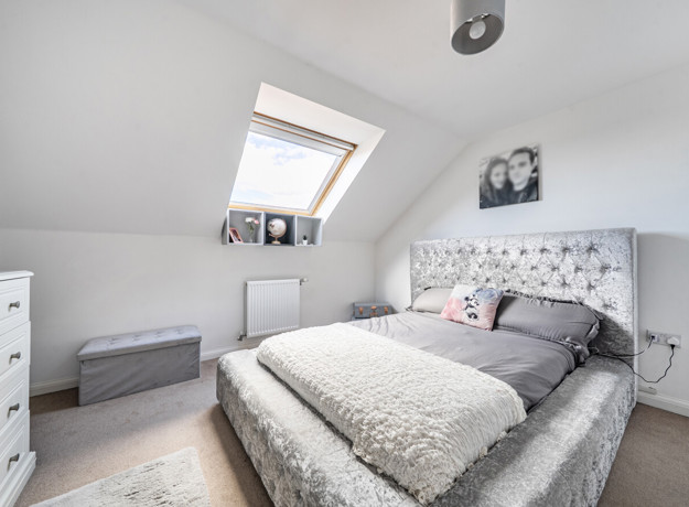Bedroom with double bed, chest of drawers and roof window.