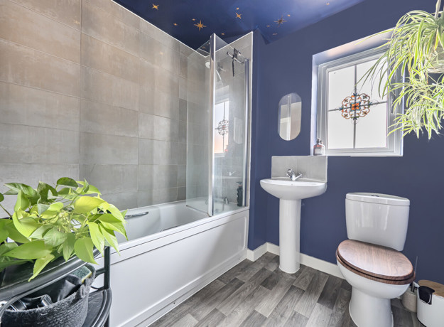 Bathroom with bath, shower screen, wash basin, toilet and window.