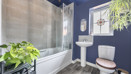 Bathroom with bath, shower screen, wash basin, toilet and window.