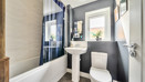 Modern bathroom with bathtub, sink and toilet, with a dark wall and beige tiles.