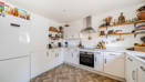 White kitchen with fitted units, open shelving and integrated oven.