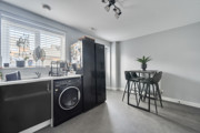 Kitchen view with counter, washing machine, and window with blinds.
